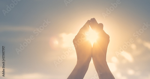 Woman's hands holding the sun at dawn. Freedom and spirituality concept. 