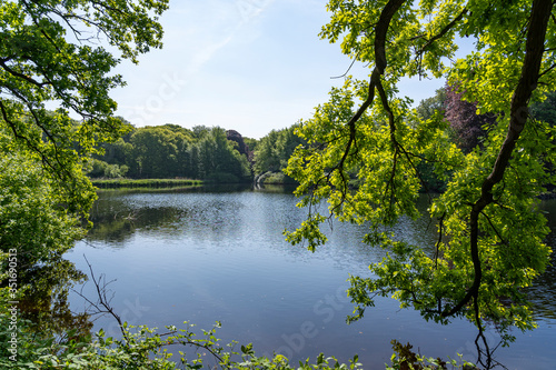 A view between the overhanging branches with fresh leaves, over the pond in the park De Horsten in Wassenaar, the Netherlands photo