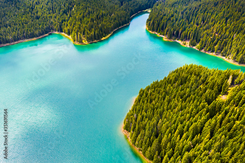 Turquoise water in a mountain forest lake with pine trees. Aerial view of blue lake and green forests. View on the lake between mountain forest. Over crystal clear mountain lake water. Fresh water photo