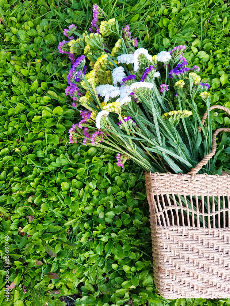View of a straw ladies bag with flowers on a background of grass. View of a straw ladies bag with flowers on a background of grass.