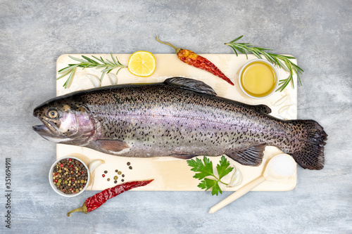 fresh trout with spices and seasonings on gray background