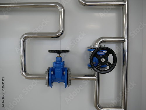 Two blue mainline water ball valve with black handles mounted on curved stainless steel pipes on the exhibition stand photo