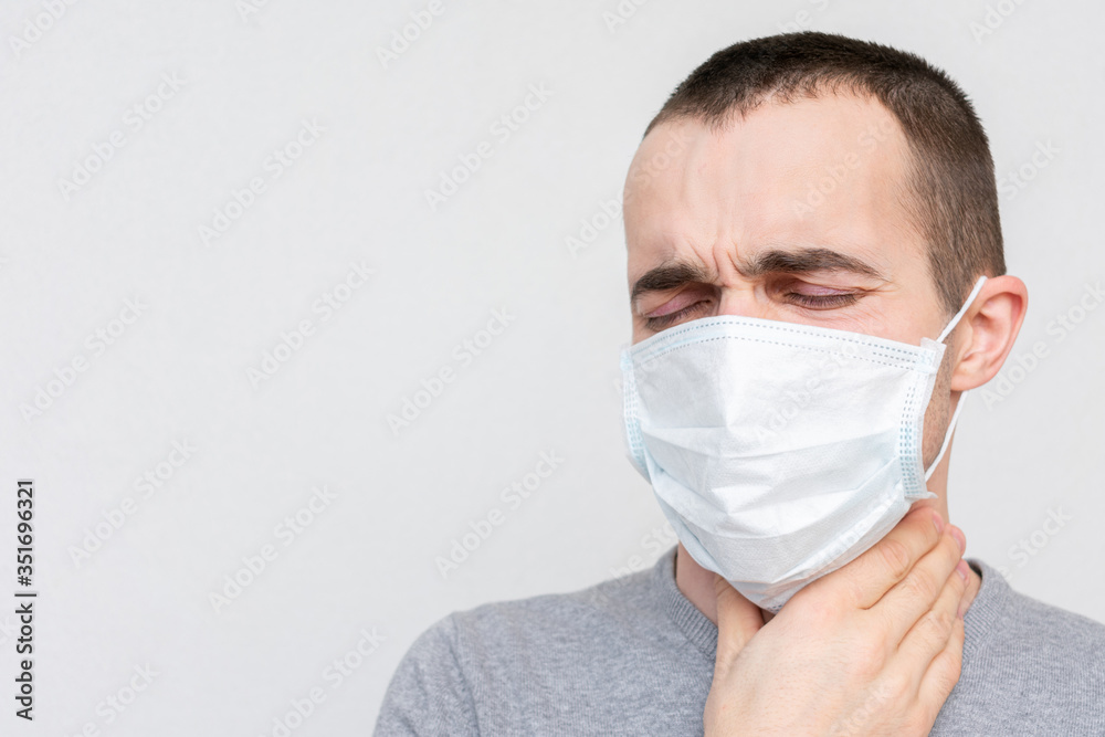 Young man in a medical mask has a sore throat, a guy has the flu, portrait, closeup Young man in a medical mask has a sore throat, a guy has the flu, portrait, closeup