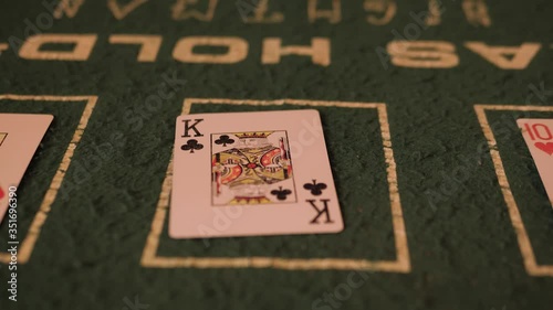 Male hand flips playing cards on a green table. Close-up. In the background are people in bright, colorful clothes.