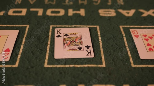 Male hand flips playing cards on a green table. Close-up. In the background are people in bright, colorful clothes.