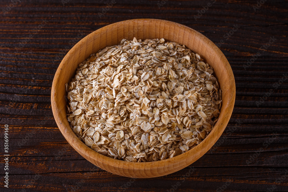 raw oatmeal on a wooden rustic background raw oatmeal on a wooden rustic background
