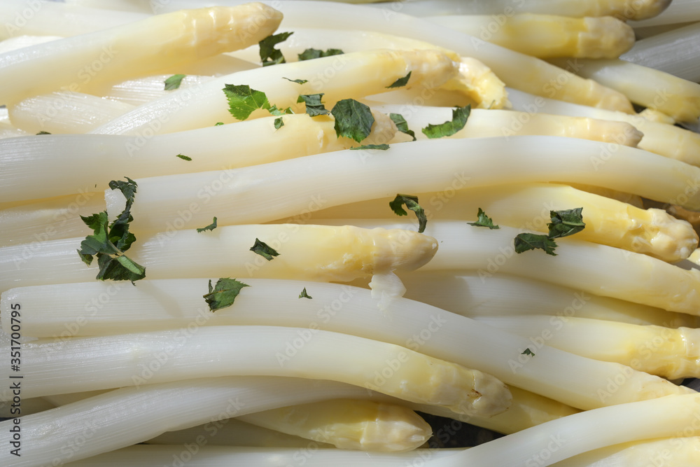 Cooked white asparagus with herb garnish as a full frame background Cooked white asparagus with herb garnish as a full frame background
