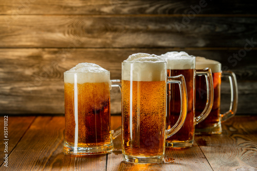 light beer with foam in mugs on a wooden table