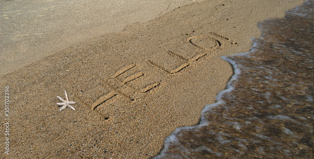 Mensagem em inglês escrita na areia de uma praia junto ao mar com pequena onda em movimento e uma estrela do mar - Hello - obrazy, fototapety, plakaty 