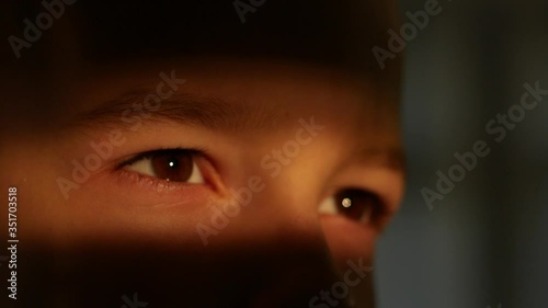 Close up of the brown eyes of a child boy in a strip of light