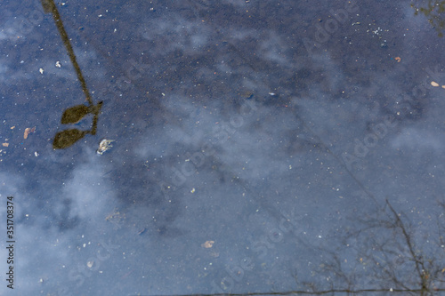 Reflection of the sky in a puddle on the asphalt. Blue background. Spring is on the street.