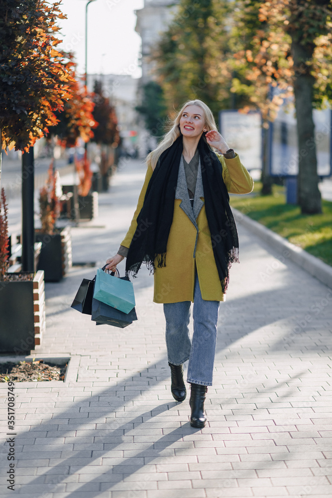 cute attractive blonde woman with packages on the street in sunny weather. shopping and positive emotions.