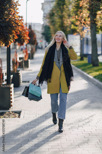 cute attractive blonde woman with packages on the street in sunny weather. shopping and positive emotions.