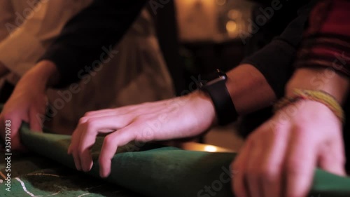Several pairs of hands fold green cloth, inside which are casino chips and buckwheat. Close-up.