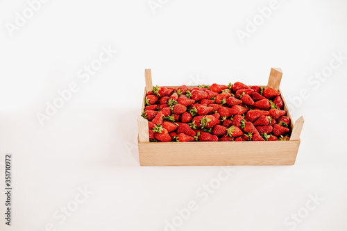 Wooden box with strawberries on the white background with copy space