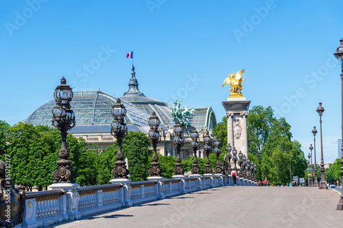 People walking on Pont Alexandre III with the Grand Palais in the background during Coronavirus epidemic - Paris, France photo