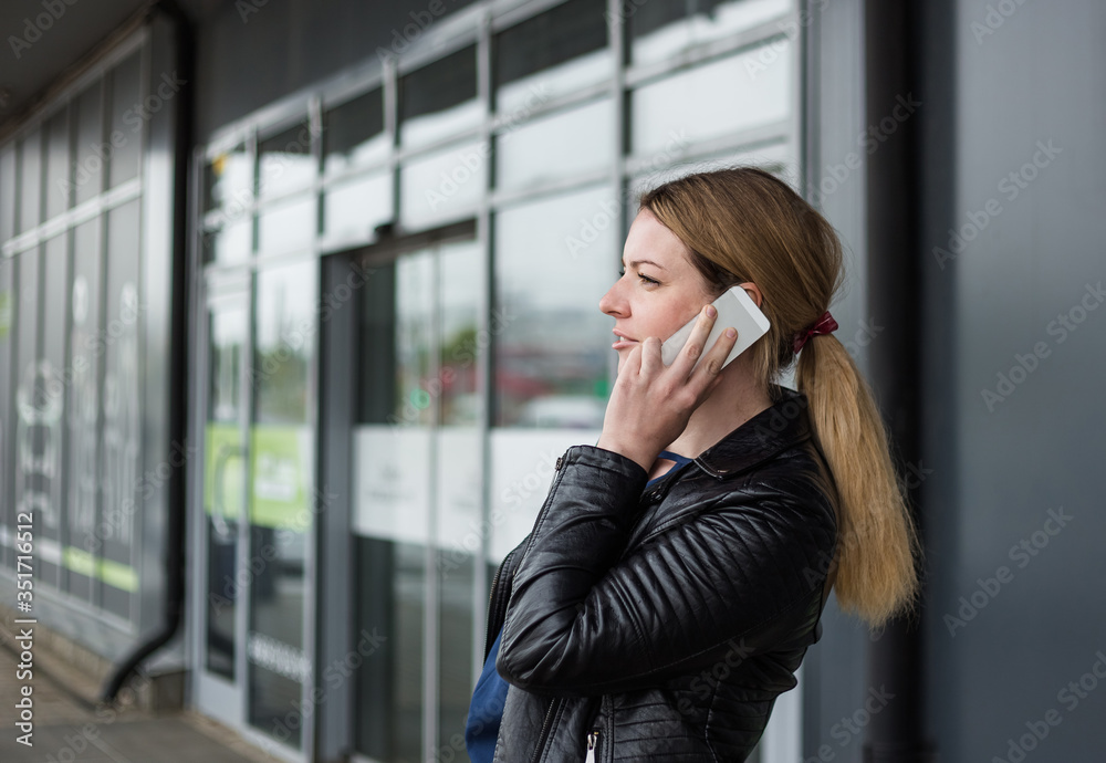 A young woman is talking on the phone near a shopping center. A young woman is talking on the phone near a shopping center.