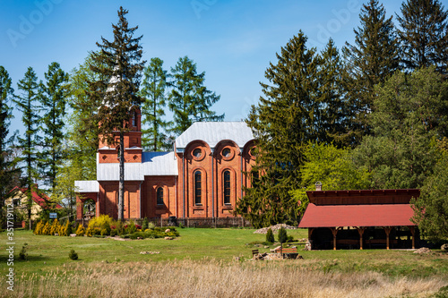 Former Orthodox church, nowadays Catholic religion church, building side view behind tree. Suchawa village in Poland, lubelszczyzna, Europe. photo