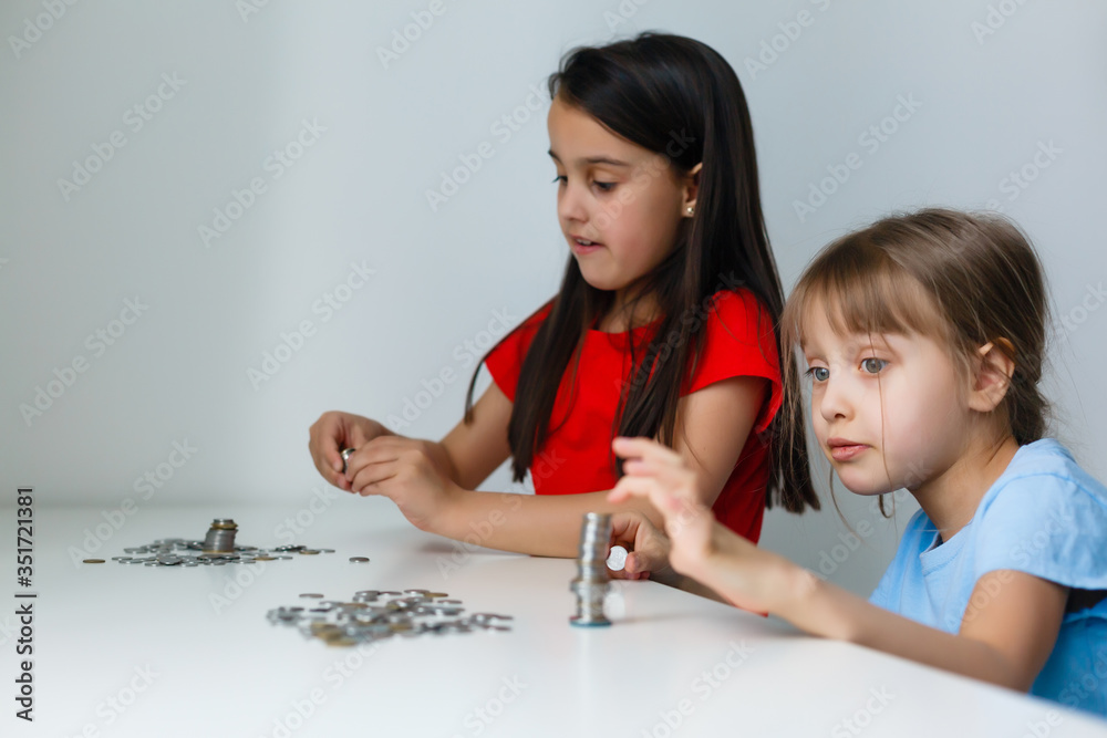 portrait of little girls sitting at table and calculating money portrait of little girls sitting at table and calculating money