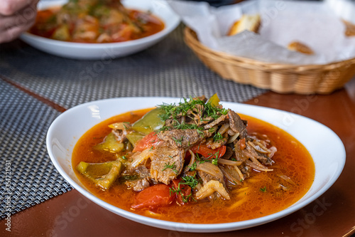 Dish with traditional asian noodle lagman with meat and vegetables on wooden table.