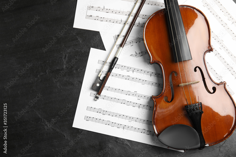 Fototapeta premium Violin, bow and note sheets on stone table, flat lay