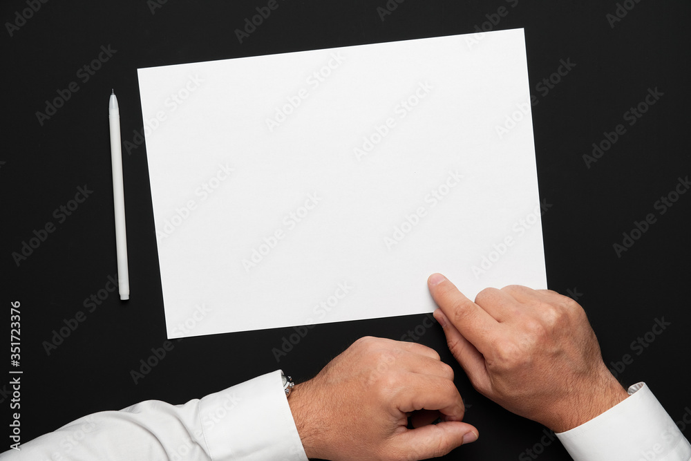 a blank sheet of paper and a businessman's hands on a black table, a white shirt and a wrist watch, a top view-a template for any text or inscription a blank sheet of paper and a businessman's hands on a black table, a white shirt and a wrist watch, a top view-a template for any text or inscription
