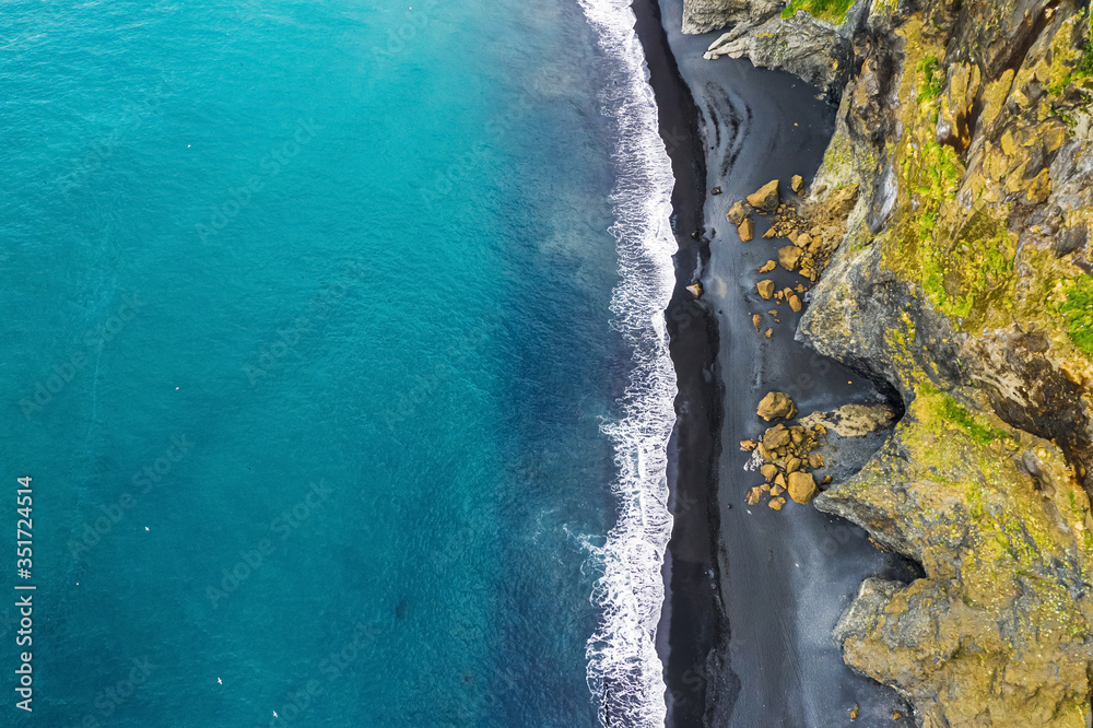 Top down view of Icelandic coastline, black sand beach of Dyrholaey cape, iconic site on Golden Circle famous touristic route in Iceland.