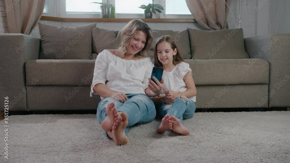 Happy caucasian family mum and cute little kid daughter laugh use smartphone online distance talk funny face and smile slow motion Happy caucasian family mum and cute little kid daughter laugh use smartphone online distance talk funny face and smile slow motion