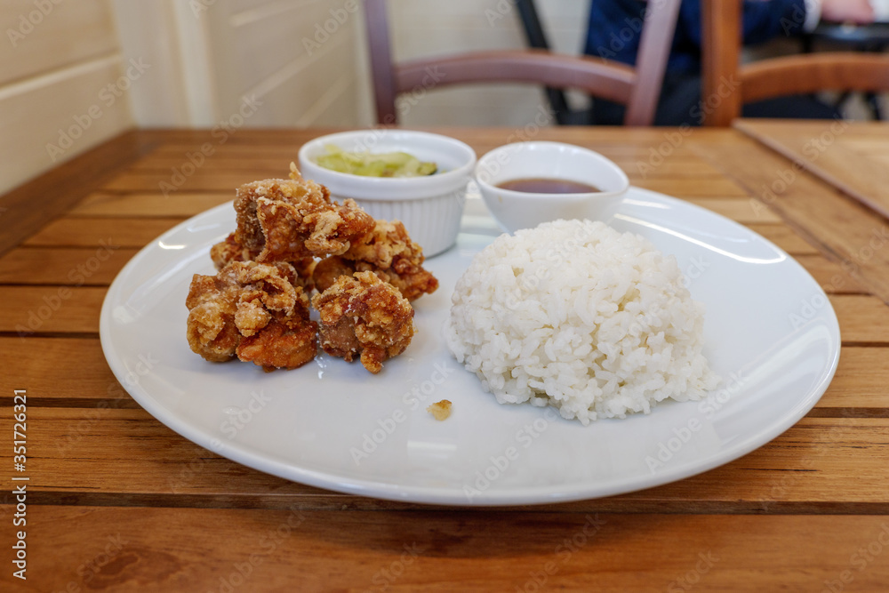 Selected focus view at homey meal style of Karaage or Japanese fried chicken serve with miso soup, salad and steamed rice on side, on wooden table in Japanese restaurant. 