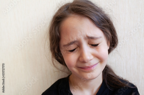 Portrait of a girl of 8 years old crying and sad on a light background
