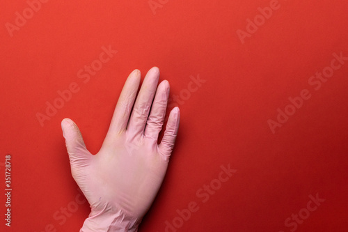 Hand glove holding Protection covid. Medical antibacterial sanitizer lab gloves - Virus protection equipment on red background. Dangerous Novel virus COVID-19, pandemic risk alert. photo