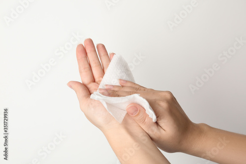 Obraz na płótnie Woman cleaning hand with antiseptic wipe on light background, closeup