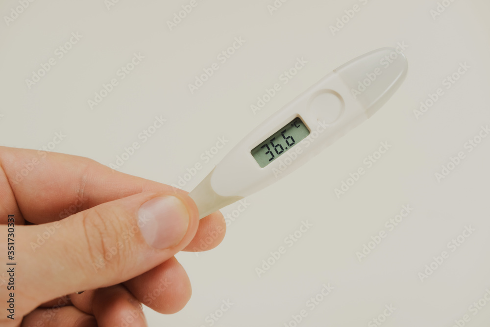 The thermometer in a man's hand shows a normal temperature of 36.6
