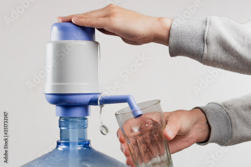 Fotografía A man pours water from a bootle into a glass with the help of a pump (cooler) on