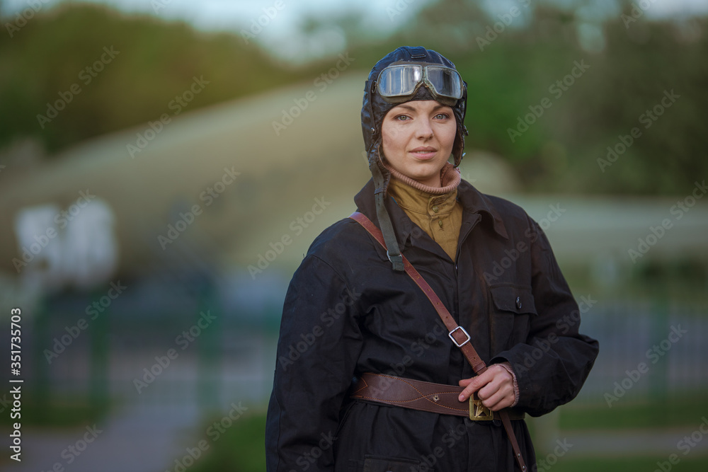 A young female pilot in uniform of Soviet Army pilots during the World War  II. Black flying jumpsuit, helmet and goggles. Photo in retro style. Stock  写真 | Adobe Stock