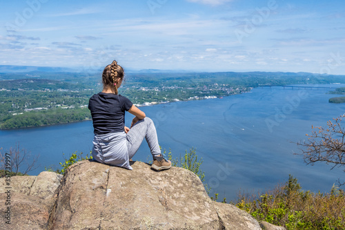 Teenage girl sits on the cliff of Storm King Mountain