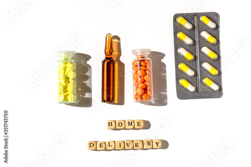 Flat lay of medical bottles, blisters with pills and capsules with home delivery text. Pharmaceutical supply for customers concept photo