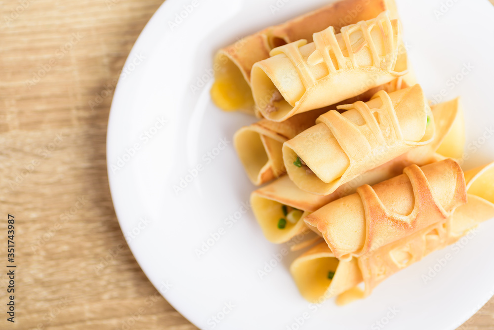 Thai dessert (Khanom Tokyo), pancake roll stuffed with minced pork on white plate Thai dessert (Khanom Tokyo), pancake roll stuffed with minced pork on white plate