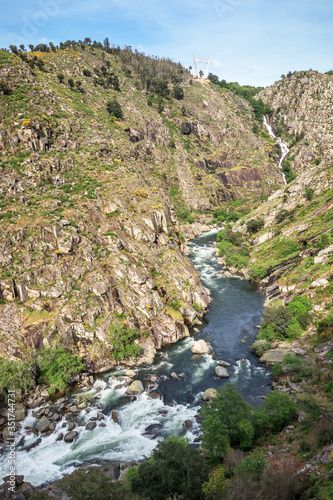 Landscape of the Paiva gorge with the Paiva river and its rapids in the foreground and the Aguieiras waterfall in the background, near Arouca in Portugal.