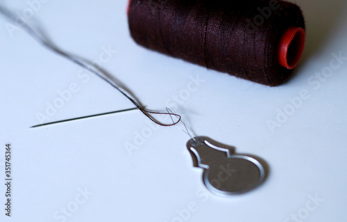 Needle threader on white background. Needle threader is a device for helping to put thread through the eye of a needle. photo