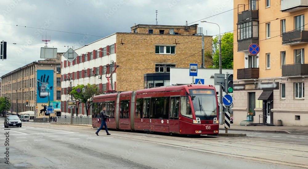 Obraz premium City street in spring, a man crossing the street moves to the tram
