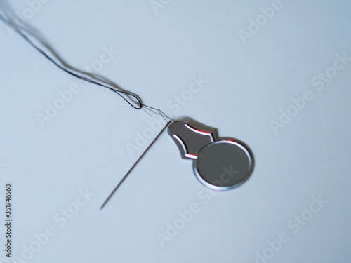 Needle threader on white background. Needle threader is a device for helping to put thread through the eye of a needle. photo