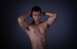 Muscular model Asian young man on Gray background. Portrait of strong brutal guy with trendy hairstyle. Sexy naked torso, six pack abs. Male flexing his muscles. Sport workout bodybuilding concept.