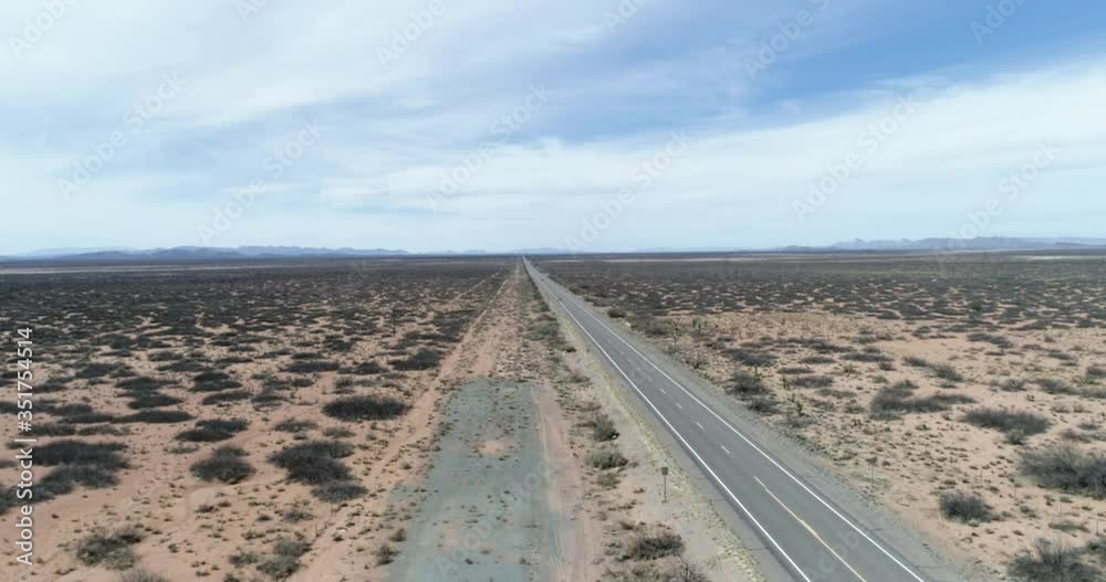 Ground level to high wide establishing shot of long straight road in southern New Mexico Ground level to high wide establishing shot of long straight road in southern New Mexico