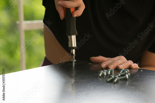 Woman assembling furniture at home using screwdriver. Close up.