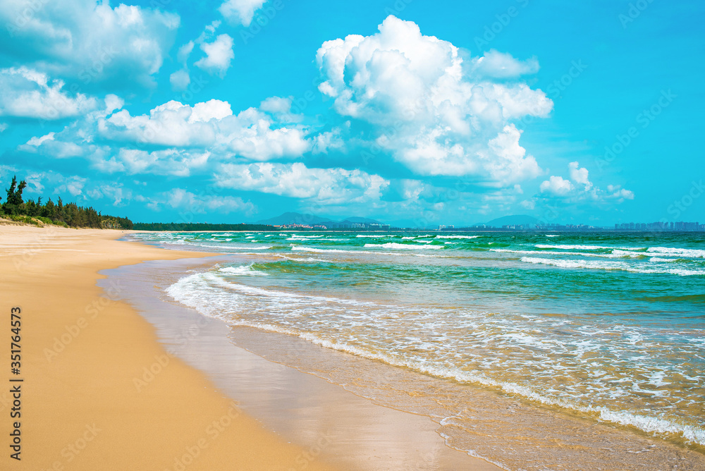 Stunning yellow sand beach, turquoise sea and blue sky with beautiful clouds. Amazing waves are washed up to the shore. South China Sea. Hainan paradise island, Sanya city. Beach Haitang Bay.