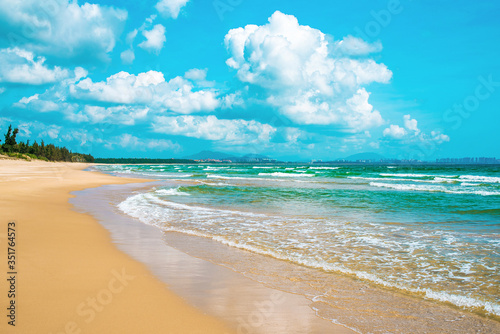 Stunning yellow sand beach, turquoise sea and blue sky with beautiful clouds. Amazing waves are washed up to the shore. South China Sea. Hainan paradise island, Sanya city. Beach Haitang Bay. photo