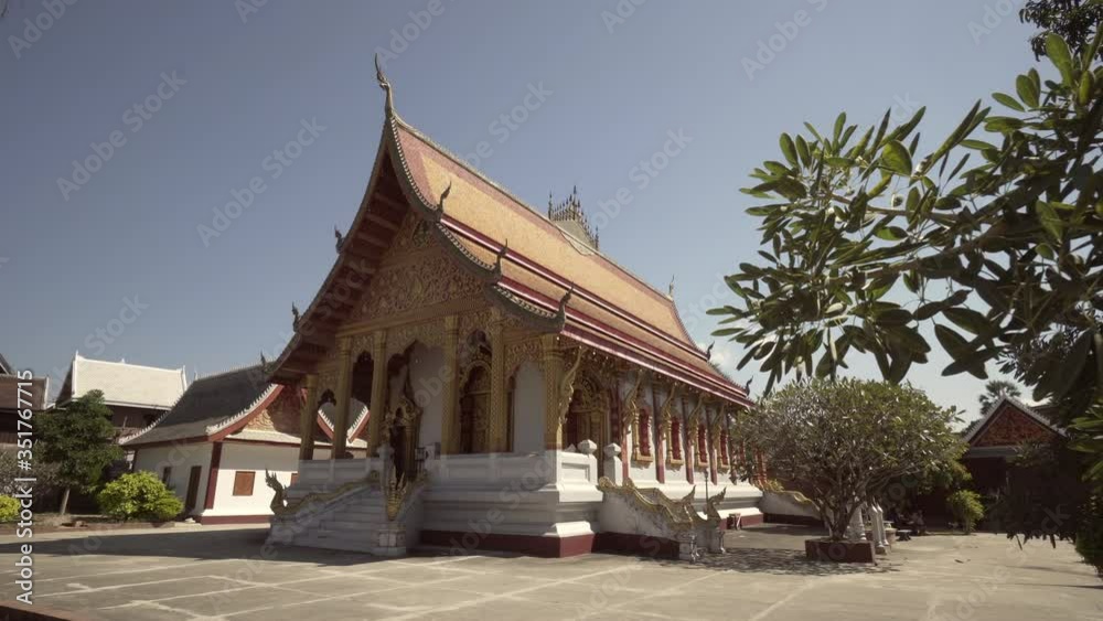 Historic famous Buddhist temple building with plants and trees against sky on sunny day - Luang Prabang, Laos Historic famous Buddhist temple building with plants and trees against sky on sunny day - Luang Prabang, Laos