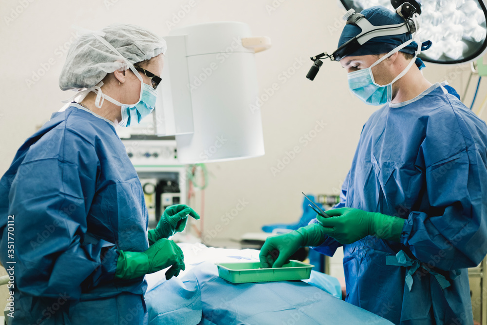 Surgeon and nurse in personal protective equipment (PPE) in operating