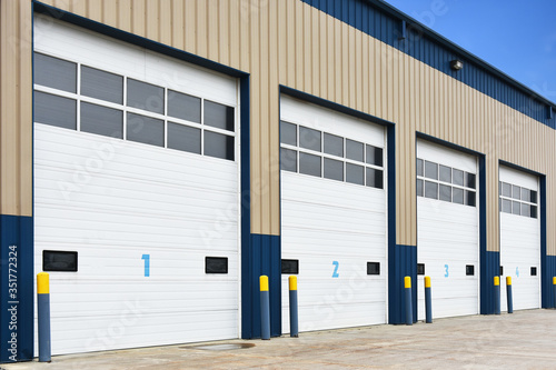 An image of a commercial building with large white numbered bay doors. 